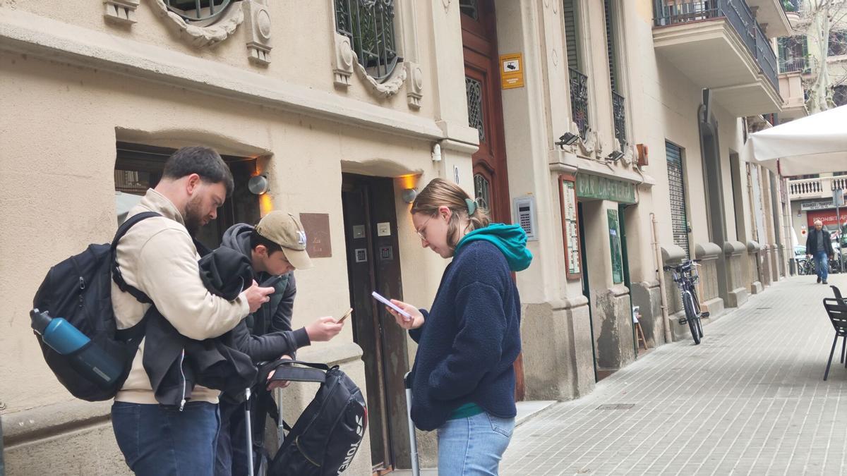Barcelona 28/2/2026 Pisos turisticos, Unos turistas esperan con sus maletas delante de un piso turistico en la calle Industia de Barcelona Foto: Imma Coy