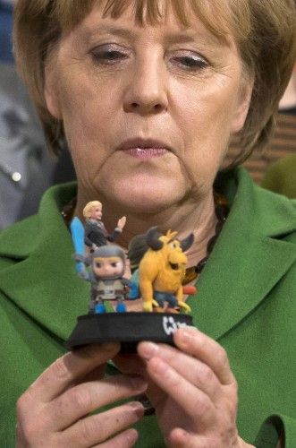German Chancellor Angela Merkel holds models of characters from a Wooga game during a visit to the office of the social games developer in Berlin