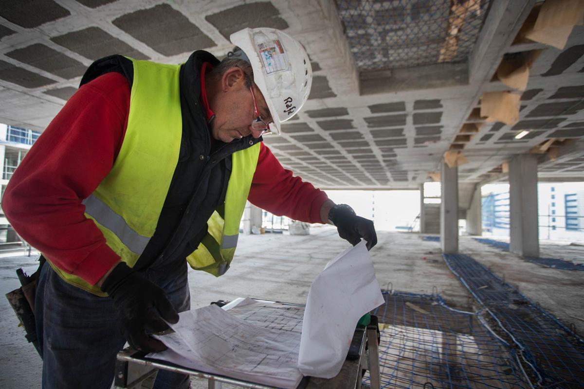 Un trabajado examina los planos de las obras de un edificio en construcción en el PAI de Malilla.