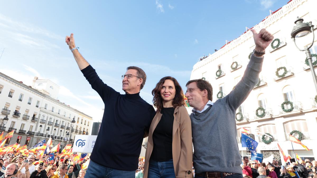 (I-D) El presidente del PP, Alberto Núñez Feijóo; la presidenta de la Comunidad de Madrid y del PP de Madrid, Isabel Díaz Ayuso,  el alcalde de Madrid, José Luis Martínez-Almeida, saludan durante una manifestación contra la amnistía, en la Puerta del Sol,