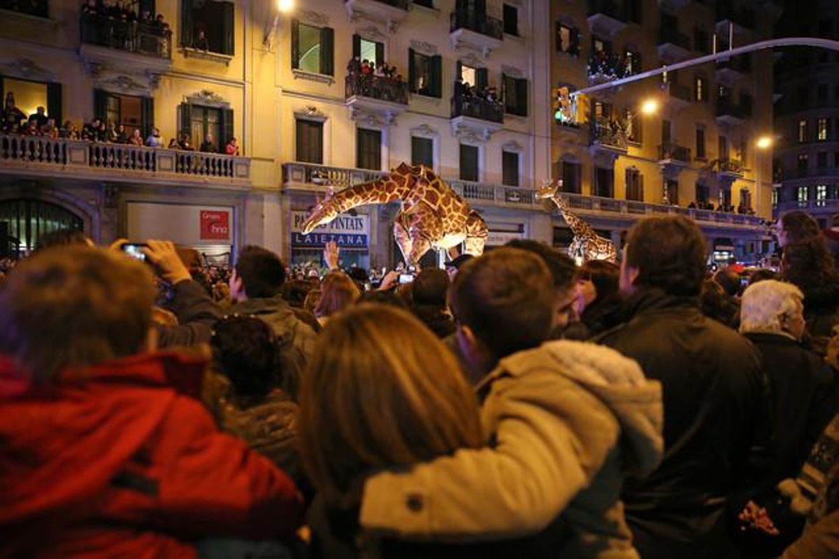 Els nens miren sorpresos les girafes que acompanyen la carrossa del rei Baltasar.