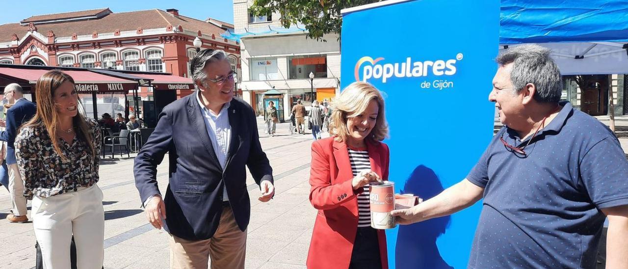 Teresa Mallada, en el centro, introduce un euro en la hucha para la campaña de Stop Muro que sostiene el afiliado Víctor Yaipén, en presencia de Pablo González y Ángela Pumariega, ayer, en la plaza del Seis de agosto. | I. S.