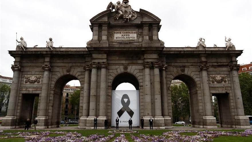 Madrid homenajea a los muertos con covid-19 con un crespón en la Puerta de Alcalá