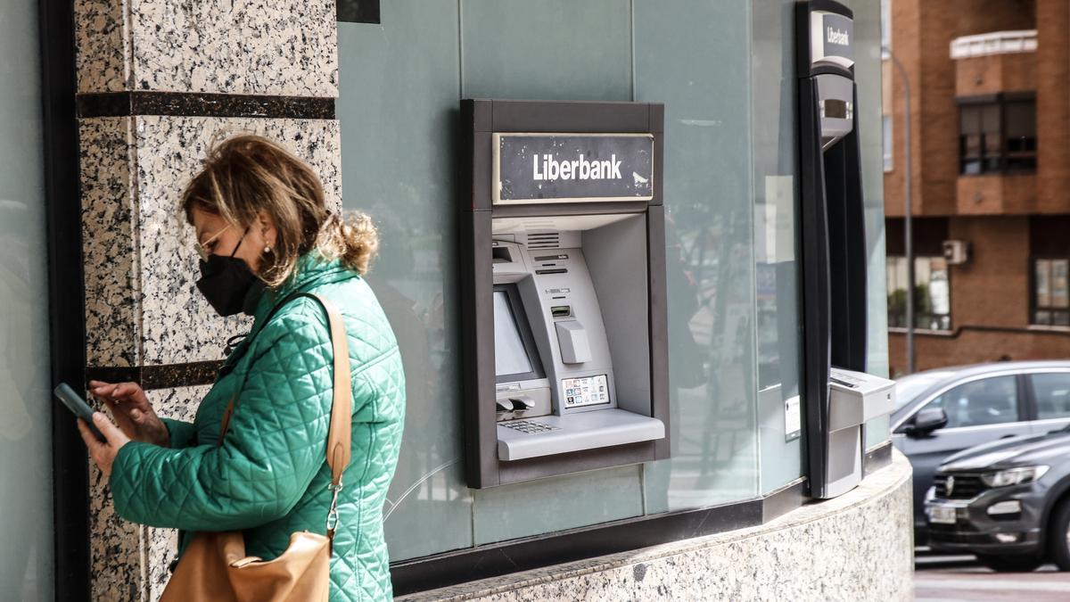 Una mujer camina hoy cerca de un cajero de Liberbank, entidad absorbida por Unicaja Banco, en Cáceres.