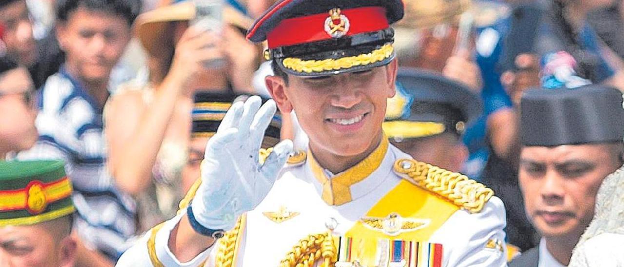 El príncipe de Brunéi saluda desde el vehículo en el desfile de la boda real por las calles de Bandar Seri Begawan.