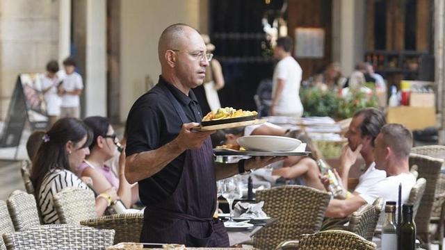Un cambrer servint a la plaça de la Independència de Girona en una imatge d’arxiu. | MARC MARTÍ