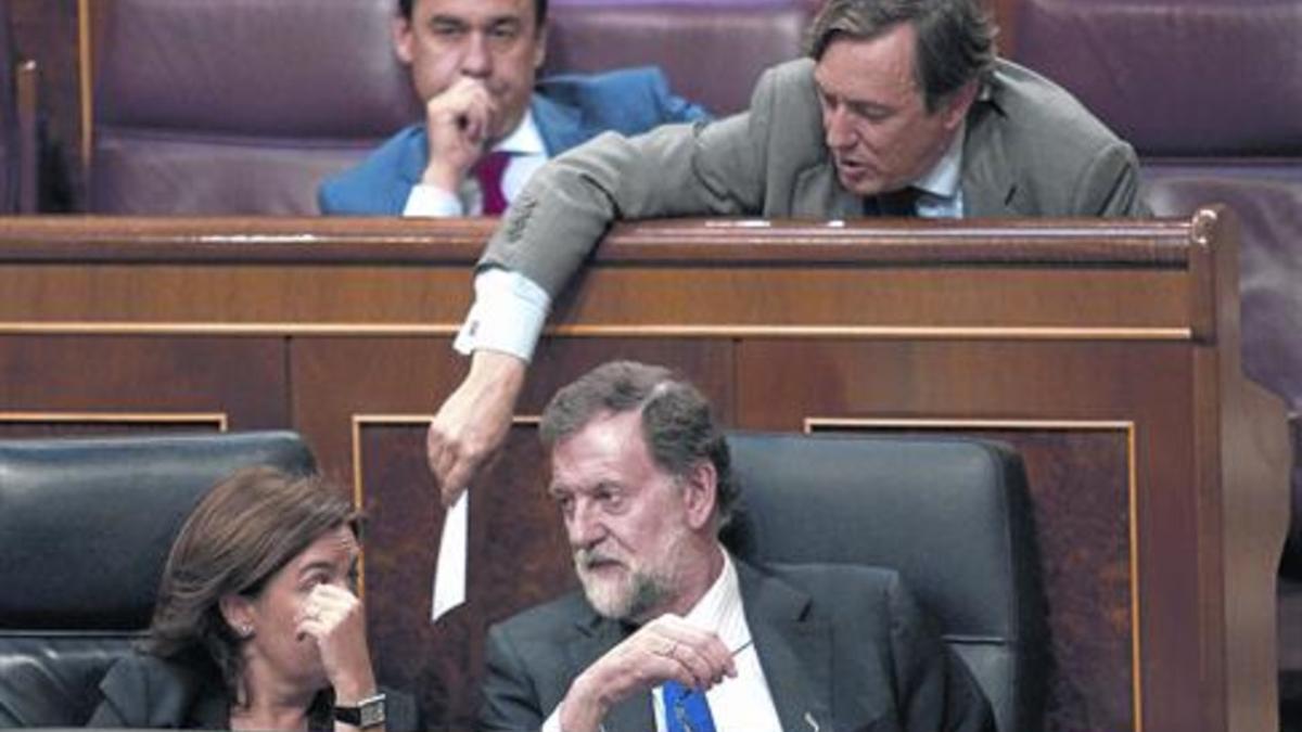 Mariano Rajoy y Soraya Sáenz de Santamaría hablan en el banco azul mientras Rafael Hernando les pasa una nota.