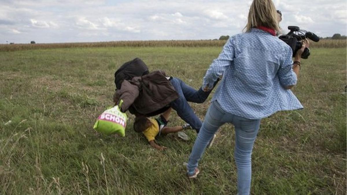 Varios periodistas grabaron a la reportera agrediendo a los inmigrantes. En este caso, tiró al suelo a un hombre que llevaba a un niño en brazos.
