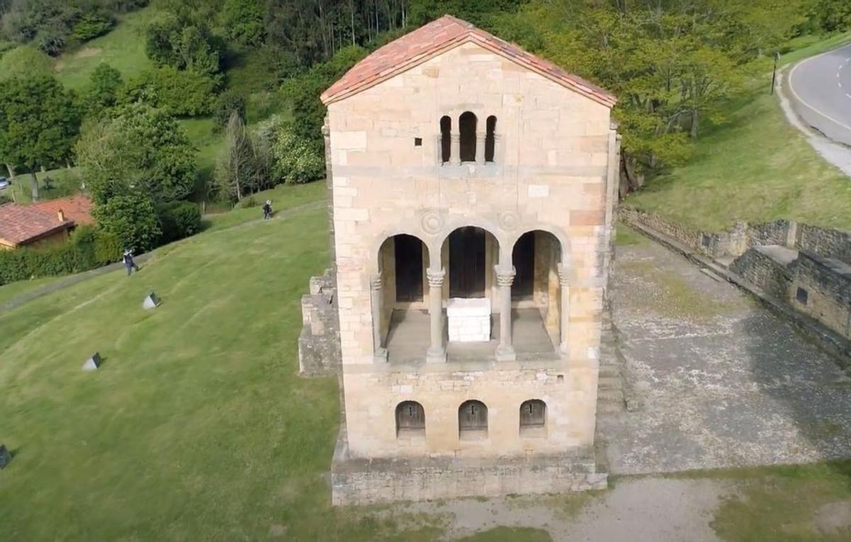 Arriba, una imagen aérea de Santa María del Naranco incluida en el vídeo promocional; sobre estas líneas, una senda habilitada en el monte. | LNE