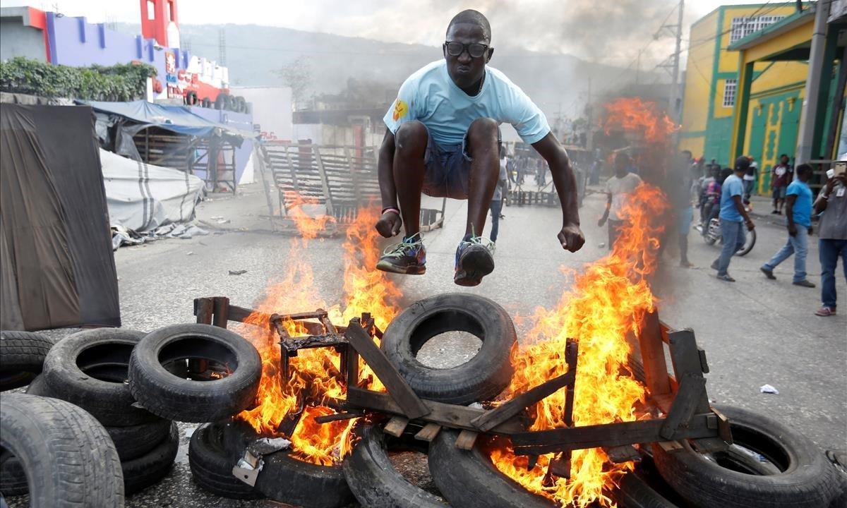 Un manifestante salta sobre una barricada en llamas durante una protesta contra el gobierno en las calles de Puerto Príncipe, Haití.