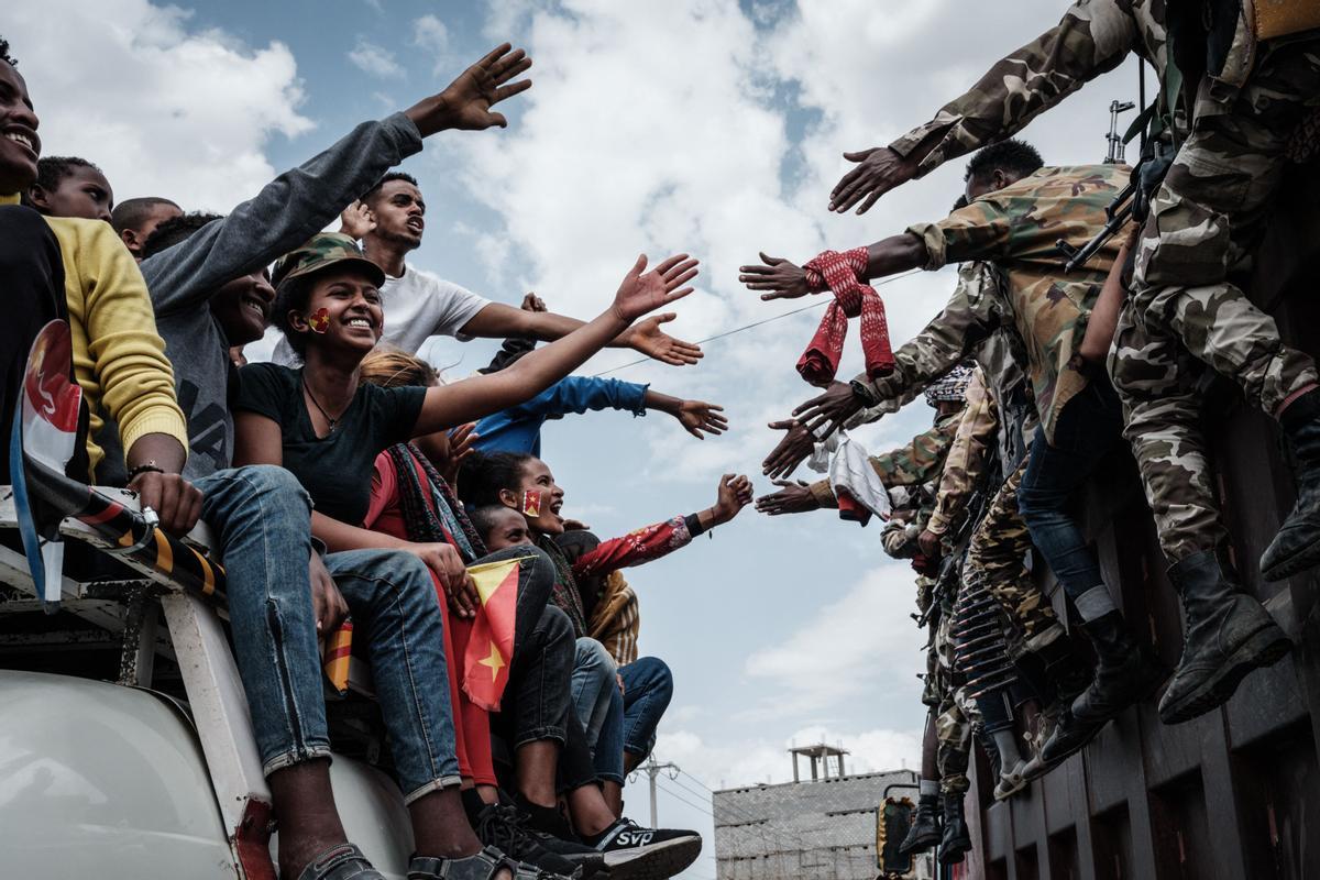 Personas en un autobús intentan tocar las manos de los soldados de la Fuerza de Defensa de Tigray (TDF) en un camión cuando llegan a Mekele, la capital de la región de Tigray , Etiopía, el 29 de junio de 2021.