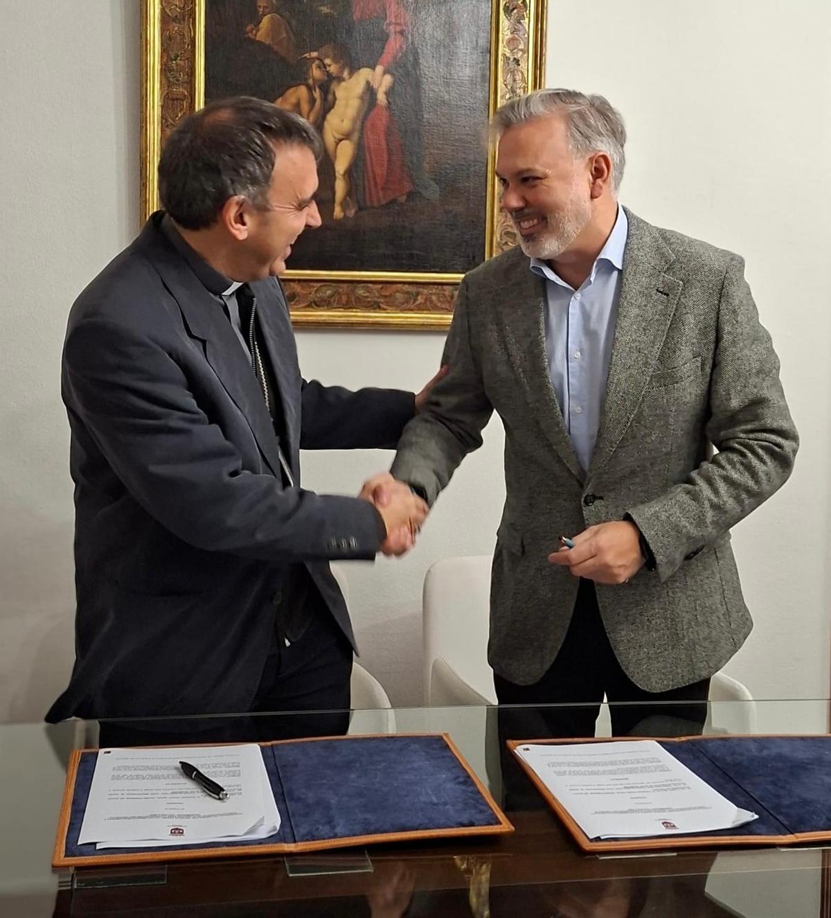 Apretón de manos del alcalde de Plasencia y el obispo, tras la firma de los convenios.