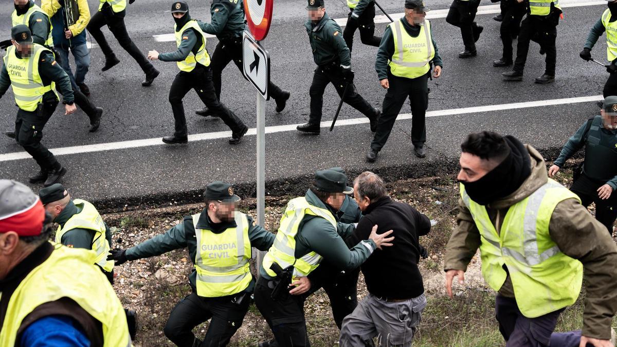 Un agente de la Guardia Civil sujeta a un agricultor en la autovía A-42, en Illescas, Toledo.