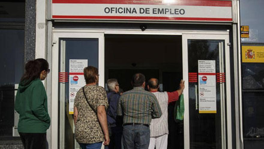 Personas hacen cola ante una oficina de empleo.