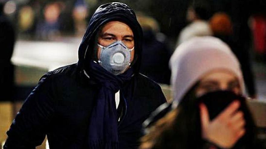 Un hombre camina por la calle con una mascarilla.