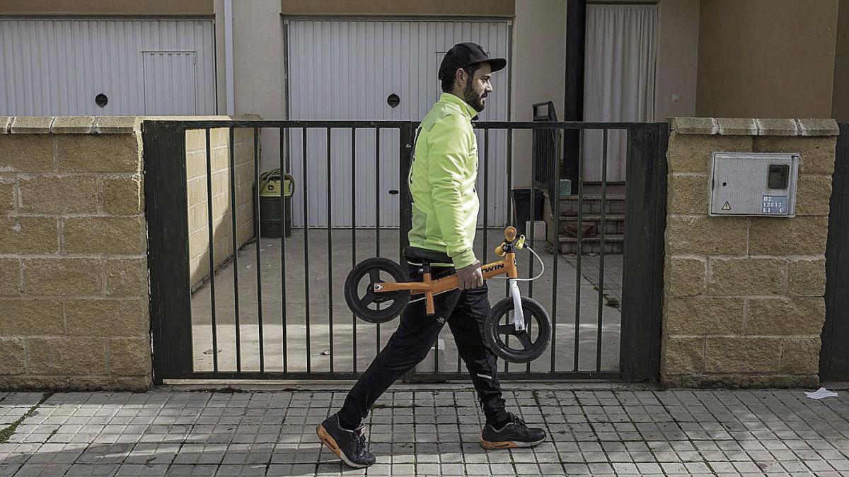 Un hombre transporta una pequeña bicicleta infantil en un pueblo de la provincia.