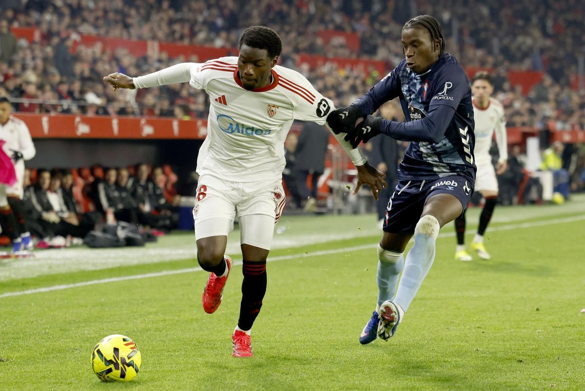 El centrocampista francés del Sevilla, Lucien Agoumé (i), disputa el balón ante el centrocampista del Celta, Ilaix Moriba.