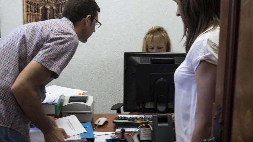 Dos padres entregando firmas para reclamar un pediatra en la ventanilla única del Ayuntamiento