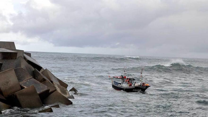 Una embarcación entrando a puerto en Puerto de Vega, a su paso junto al espigón oeste.