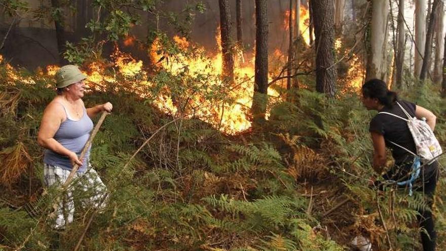 Dos vecinos, apagando el fuego en Vincios. // Lalo Villar