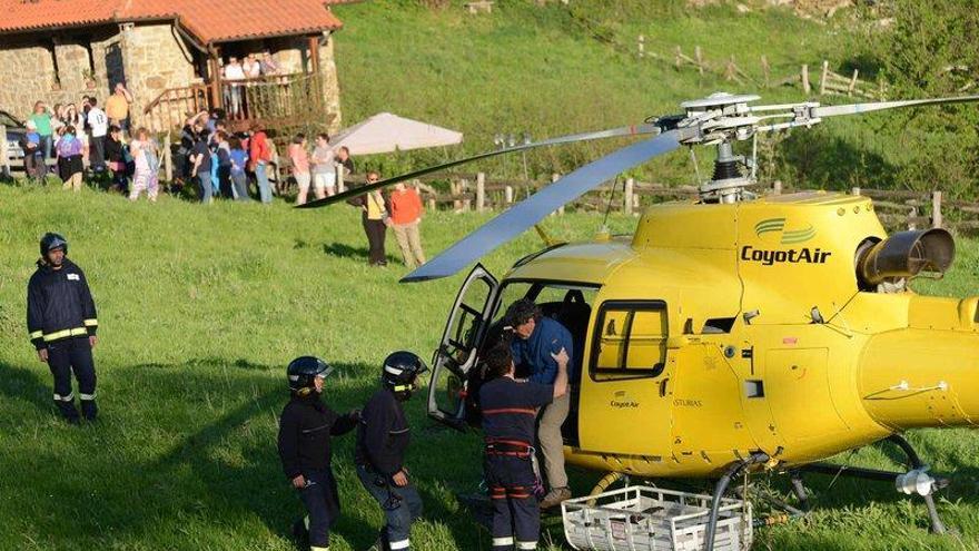 Uno de los senderistas rescatados sale del helicóptero ayudado por los bomberos, en Ladines.