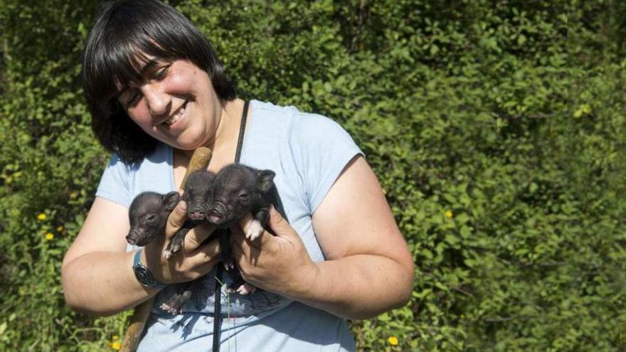 María Luisa García, voluntaria de la ONG &quot;Mundo Vivo&quot;, sostiene tres crías de cerdo vietnamita.