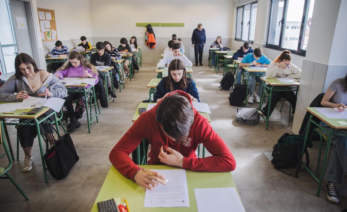 Alumnos y alumnas de secundaria, realizando un examen en clase bajo la supervisión de su profesor. Alumnos y alumnas de secundaria, realizando un examen en clase bajo la supervisión de su profesor.