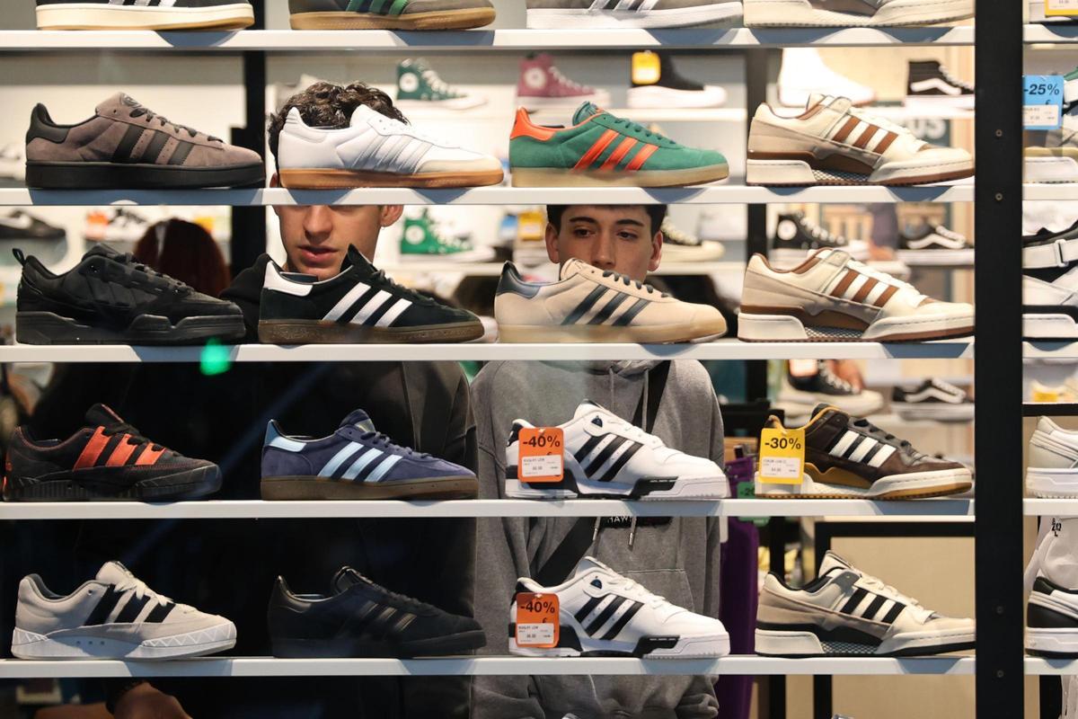Jóvenes en una tienda de calzado observan distintos modelos de zapatillas.