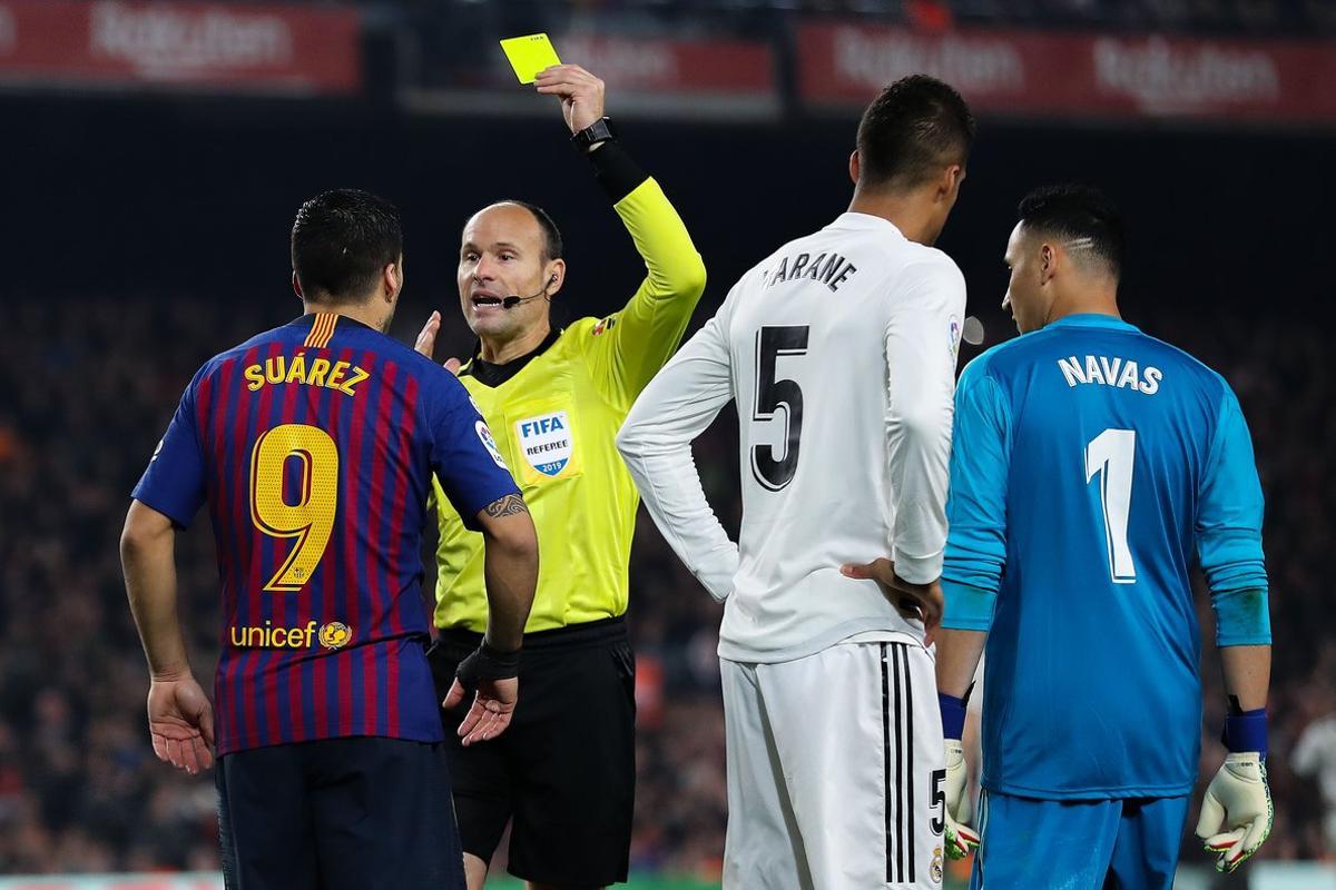 BARCELONA, SPAIN - FEBRUARY 06: Luis Suarez of FC Barcelona is shown a yellow card by the referee Mateu Lahoz during the Copa del Semi Final first leg match between Barcelona and Real Madrid at Nou Camp on February 06, 2019 in Barcelona, Spain. (Photo by Angel Martinez/Getty Images)