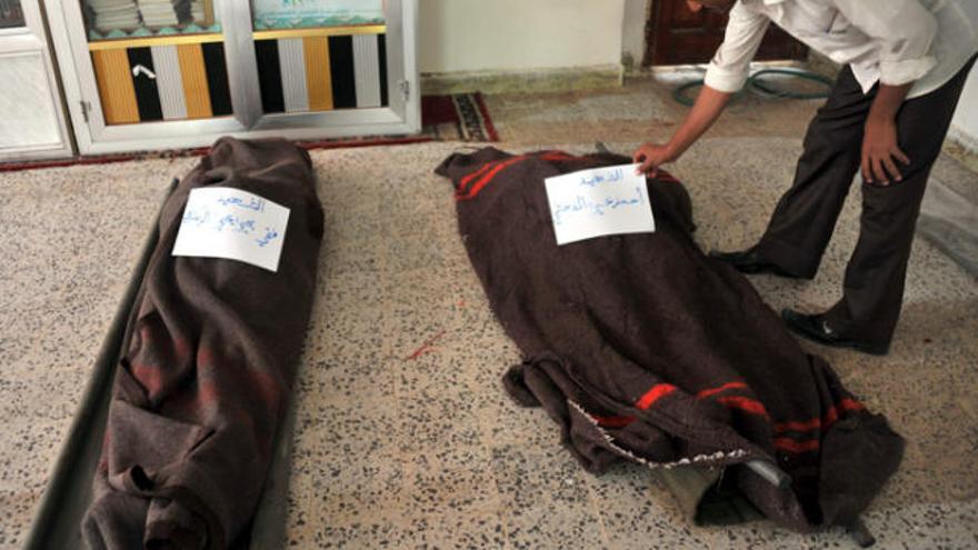 Un home col·loca una identificació en un cadàver al Iemen.