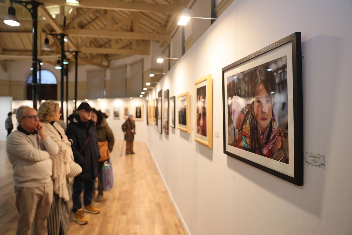 Visitantes observan los cuadros de la bienal de pintura al pastel.