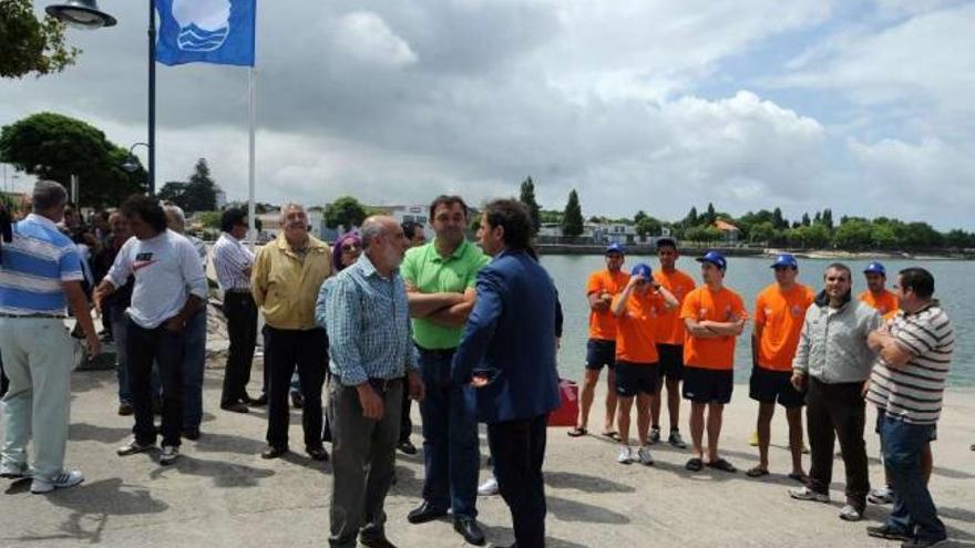 Tomás Fole, de espaldas, y Manuel Tarrío izando la bandera azul en Vilaxoán hace un año.  // Iñaki Abella