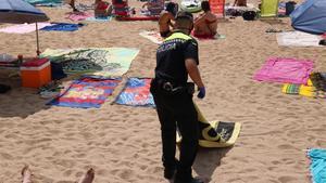 Un policía local retira toallas en la playa de Tamariu.