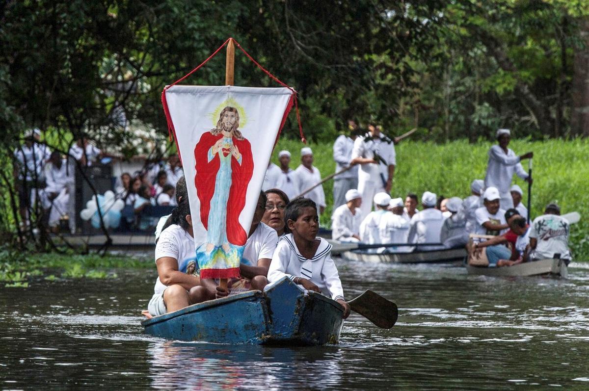 FILE PHOTO  Roman Catholic pilgrims display a banner with an image depicting Jesus Christ as they travel in a boat while accompanying the statue of Our Lady of Conception  not seen  during an annual river procession and pilgrimage along the Caraparu River in Santa Izabel do Para  in the Amazon jungle December 8  2012  Picture taken December 8  2012  REUTERS Paulo Santos File Photo