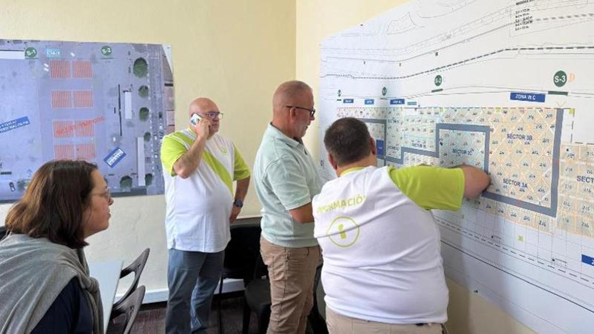 Miembros del 'staff' de los voluntarios reparten a los asistentes sobre un plano del puerto de Santa Cruz.