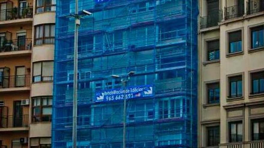 Imagen de un edificio de viviendas con la fachada en pleno proceso de rehabilitación en la plaza de los Luceros de la ciudad de Alicante.