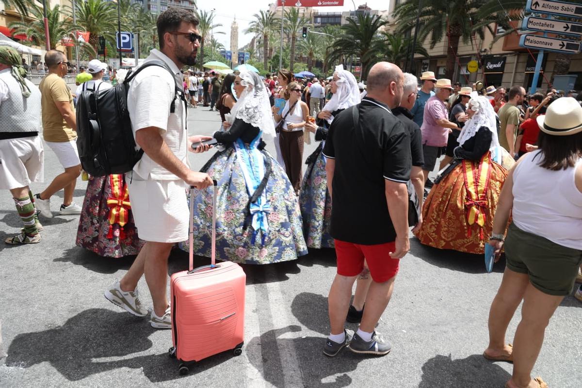 Un turista pasa con maleta ante unas bellezas.