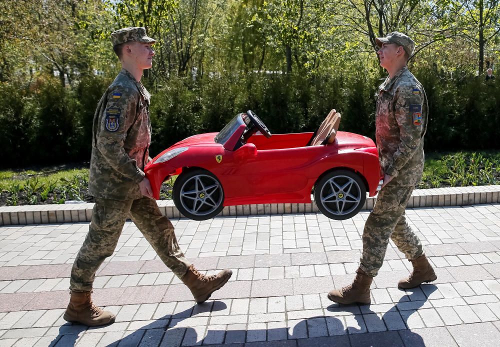 Military cadets carry a toy car in a park in ...