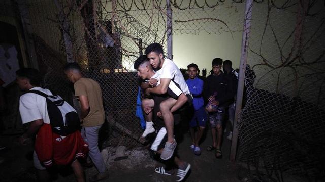 Un grup de migrants travessa una tanca trencada al sortir de Ceuta, de tornada a la localitat marroquina de Castillejos, ahir.  | ABDEL MAJID BZIOUAT / AFP