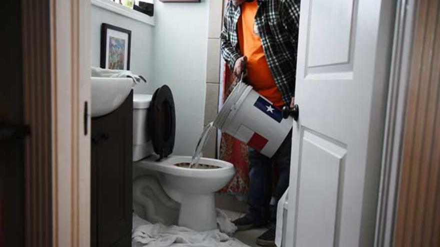 Un hombre utiliza un cubo de agua para limpiar su retrete.