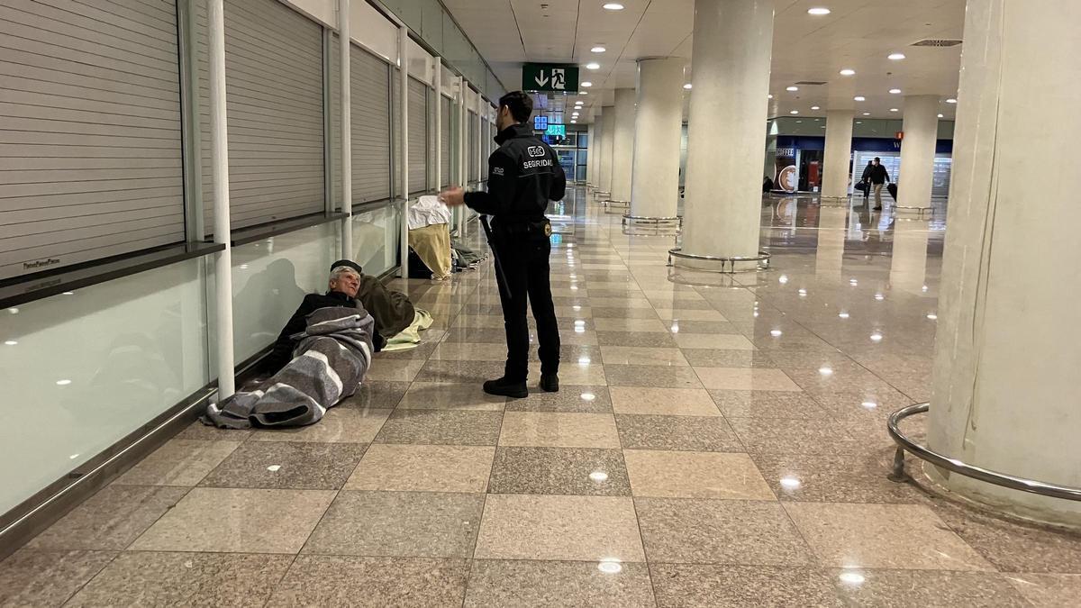 Un trabajador de seguridad del aeropuerto despierta un hombre sin hogar y le pide que abandone la terminal.