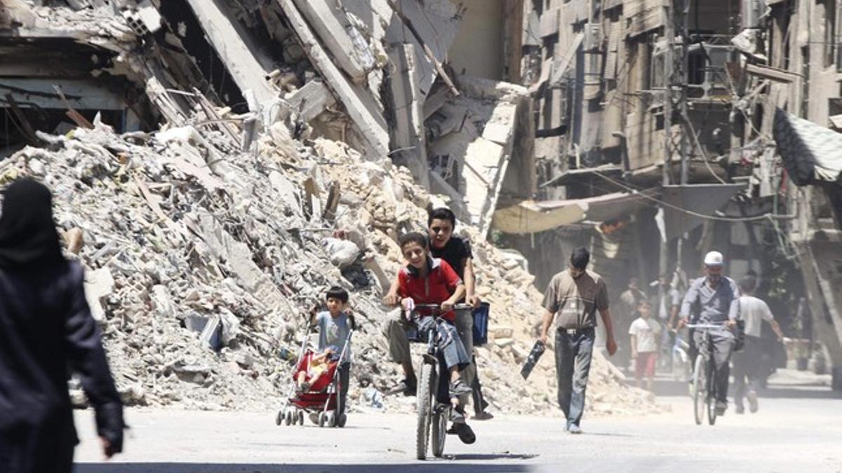 Unos niños montan en bici en las calles de Damasco (Siria).