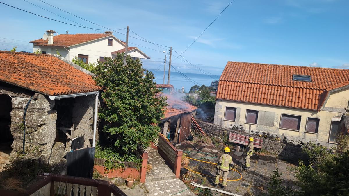 Los bomberos durante las labores de extinción del fuego en el alpendre, en el lugar de A Gándara, en Cela (Bueu).
