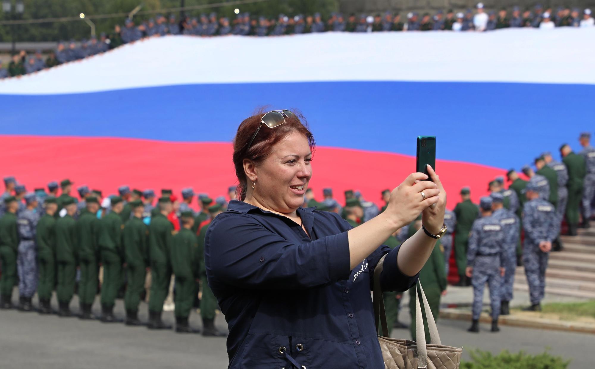 Una ciudadana rusa se fotografía junto a una bandera