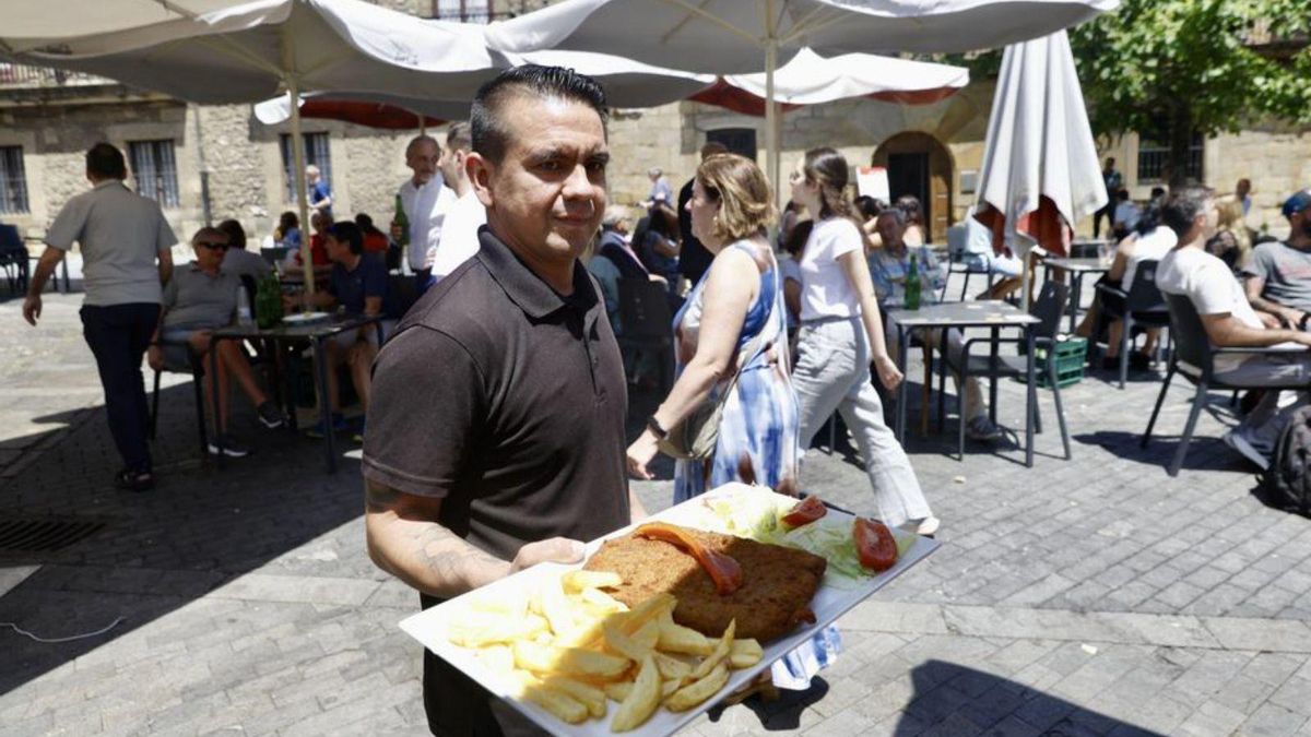 Hernán Duarte lleva un cachopu a una mesa n'Avilés.