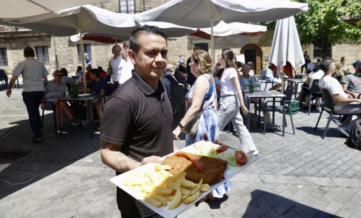 Hernán Duarte lleva un cachopo a una de las mesas de la terraza.