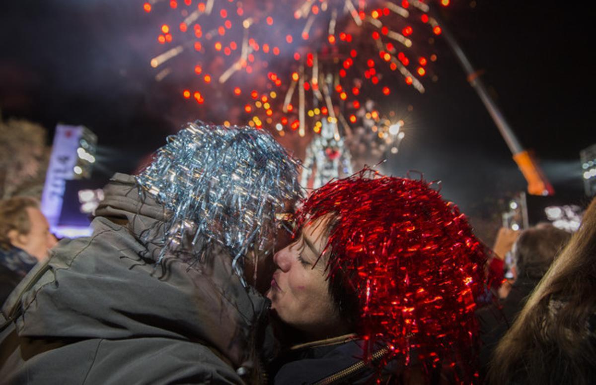 Dos joves es feliciten l’any nou, davant les fonts de Montjuïc.