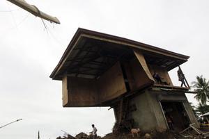 Unes quantes persones, al costat de les restes d’una vivenda arrasada per les inundacions a Iligan, al nord de Mindanao (Filipines).