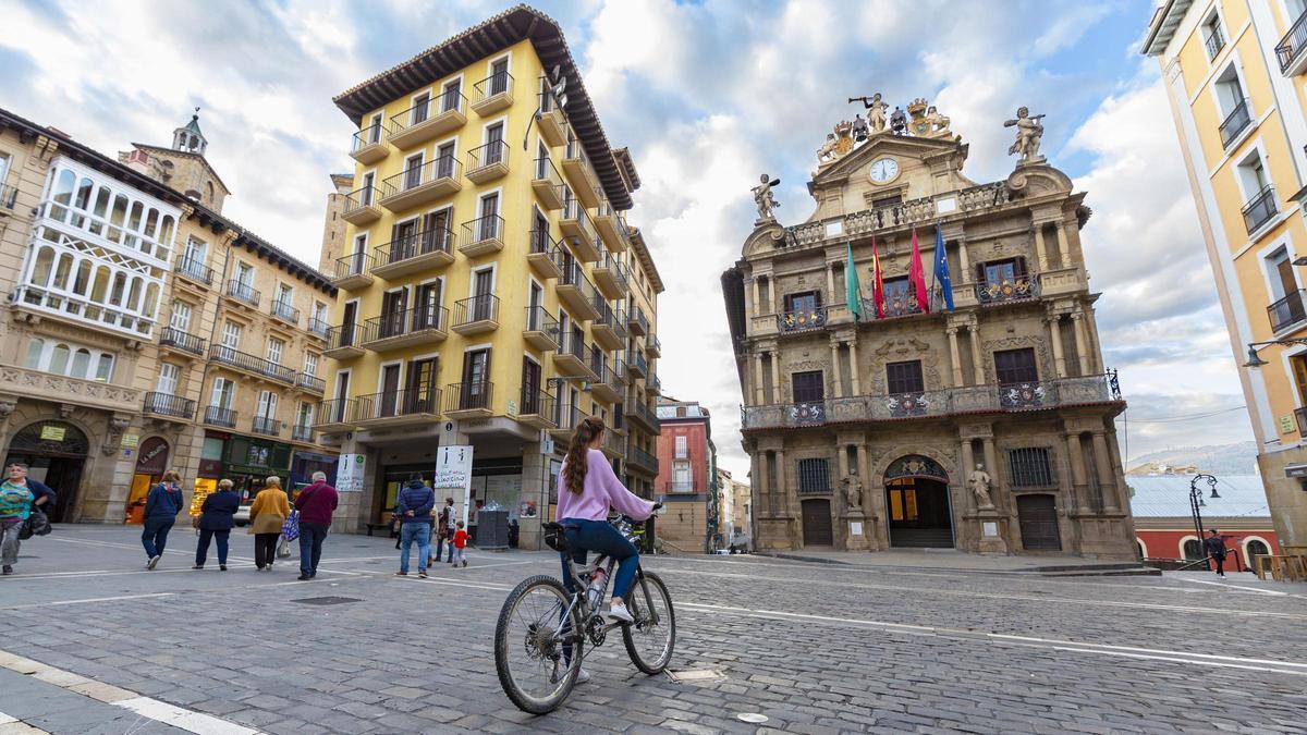 Una joven para su bicicleta ante la portada del Ayuntamiento de Pamplona.