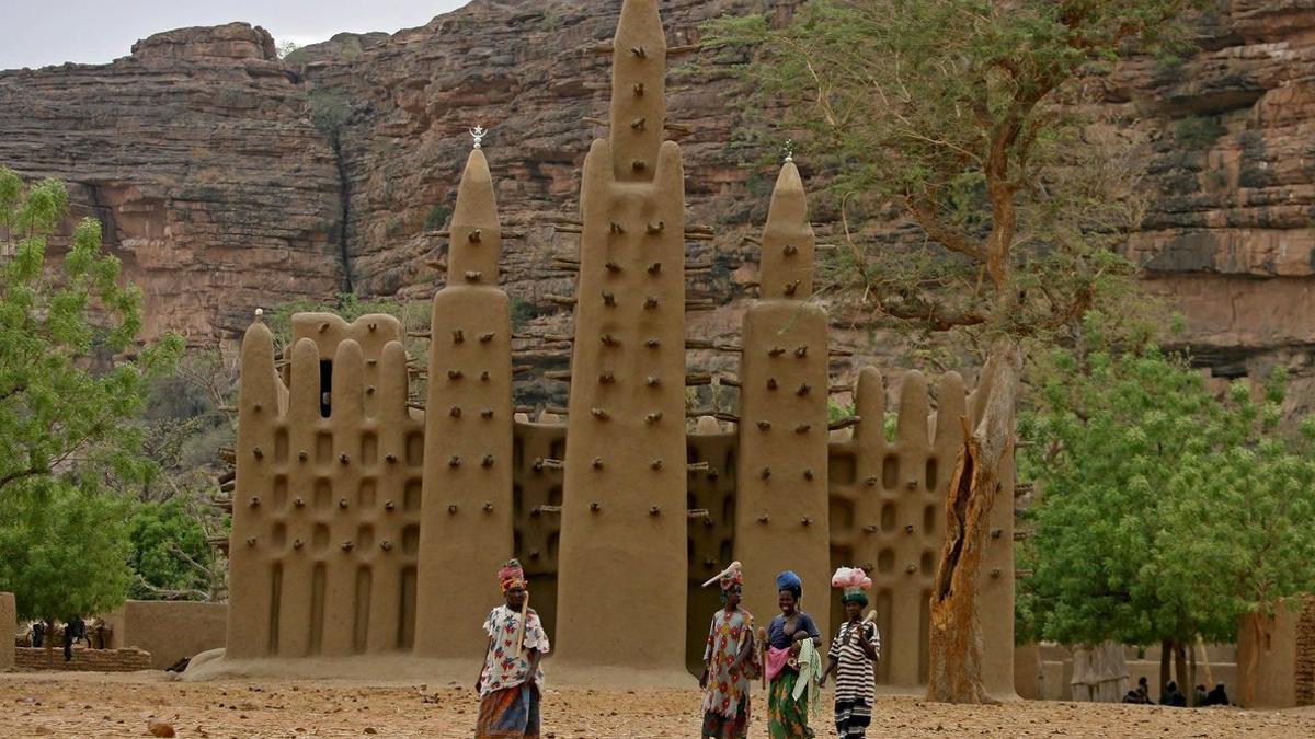 Varias mujeres pasan frente a una mezquita en una aldea dogon, en el centro de Mali.